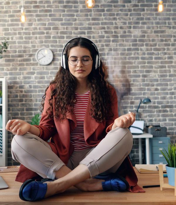 Woman doing a gentle yoga stretch at an office desk.